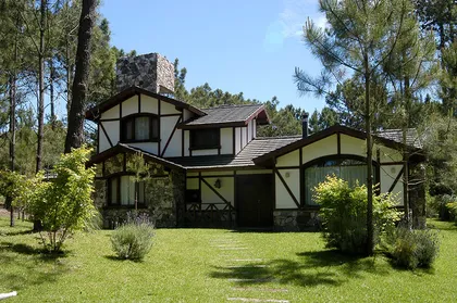 Casa rústica de campo con fachada de piedra y madera — proyecto Casa Cariló 2003, por Hugo Zawadski Arquitectos, en Cariló
