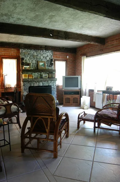 Living rústico con vigas de madera y lareira de piedra — proyecto Casa Cariló 2004, por Hugo Zawadski Arquitectos, en Cariló