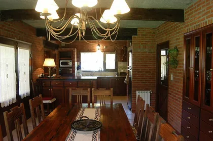 Cocina rústica con comedor integrado y paredes de ladrillo — proyecto Casa Cariló 2004, por Hugo Zawadski Arquitectos, en Cariló