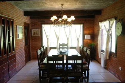 comedor rústico con paredes de ladrillo a la vista y gran mesa — proyecto Casa Cariló 2004, por Hugo Zawadski Arquitectos, en Cariló