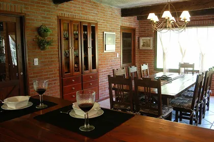 Comedor rústico con paredes de ladrillo visto y vigas de madera — proyecto Casa Cariló 2004, por Hugo Zawadski Arquitectos, en Cariló