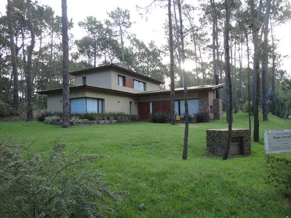 Fachada moderna-rústica con grandes ventanales en bosque — proyecto Casa Cariló 2015, por Hugo Zawadski Arquitectos, en Cariló