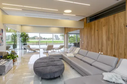 Living moderno con sofá modular y otomana circular grande — proyecto Las Caletas, por Arfuso Arquitectos, en Nordelta