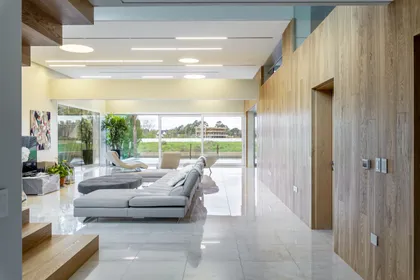 Living moderno con sofá modular y paredes de madera — proyecto Las Caletas, por Arfuso Arquitectos, en Nordelta