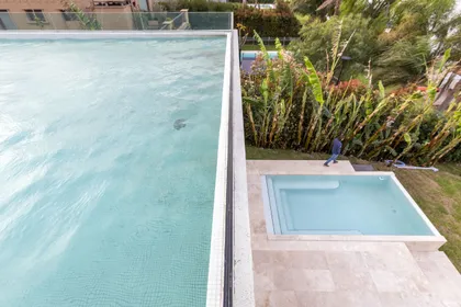 pileta de natación moderna con deck de piedra y vegetación alta — proyecto Las Caletas, por Arfuso Arquitectos, en Nordelta