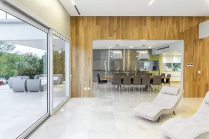 Living comedor moderno con isla y ventanales amplios y paredes de madera — proyecto Las Caletas, por Arfuso Arquitectos, en Nordelta