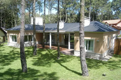 Fachada moderna con grandes ventanales y madera en entorno forestal — proyecto Casa Cariló 2005, por Hugo Zawadski Arquitectos, en Cariló