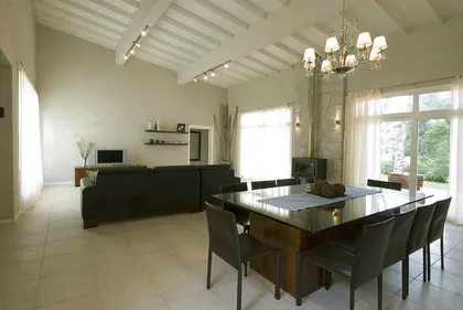Living comedor moderno con vigas expuestas y sofá negro — proyecto Casa Cariló 2007, por Hugo Zawadski Arquitectos, en Cariló