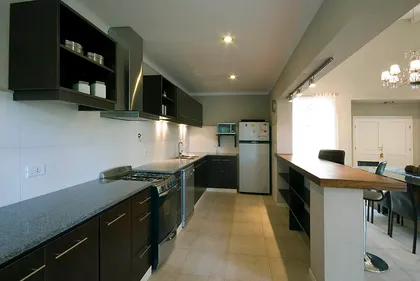 Cocina moderna con isla larga y muebles negros — proyecto Casa Cariló 2007, por Hugo Zawadski Arquitectos, en Cariló