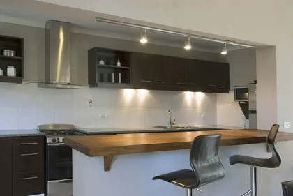 Cocina moderna con isla de madera y barra — proyecto Casa Cariló 2007, por Hugo Zawadski Arquitectos, en Cariló