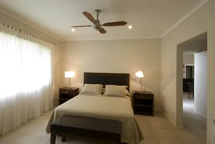 dormitorio moderno con paredes beige y cama matrimonial — proyecto Casa Cariló 2007, por Hugo Zawadski Arquitectos, en Cariló