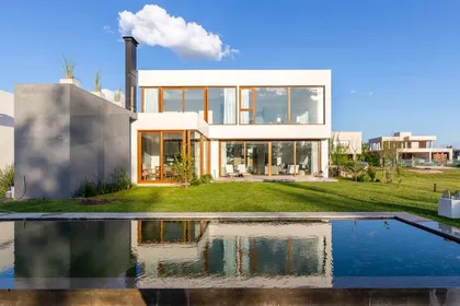 Fachada moderna con piscina infinita y amplios ventanales — proyecto Casa ME, por Estudio GR, en City Bell