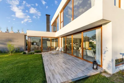 Fachada moderna con deck y grandes ventanales — proyecto Casa ME, por Estudio GR, en City Bell