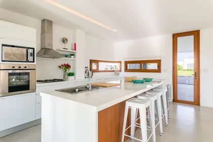 Cocina moderna blanca con isla de cascada y madera — proyecto Casa ME, por Estudio GR, en City Bell