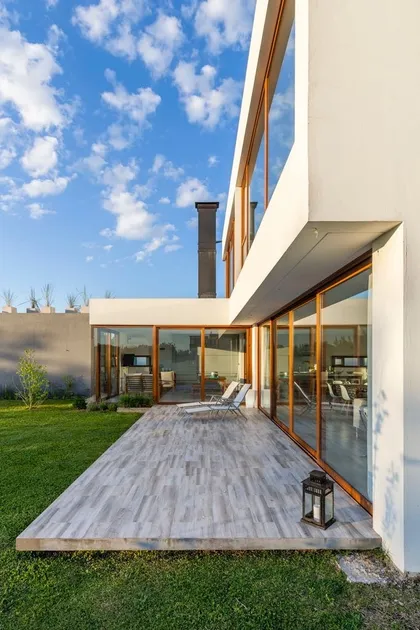 Fachada moderna con deck de madera y jardín — proyecto Casa ME, por Estudio GR, en City Bell