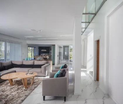 Living moderno minimalista con grandes ventanales y suelo de mármol — proyecto Casa FA, por Estudio GR, en City Bell
