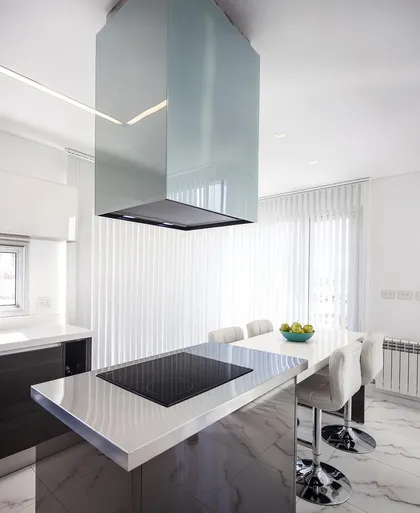 Cocina moderna con isla central y extractor geométrico — proyecto Casa FA, por Estudio GR, en City Bell