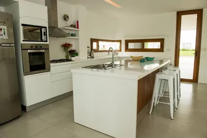 Cocina moderna con isla, blanco y acero inoxidable — proyecto Casa ME, por Estudio GR, en City Bell