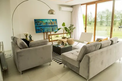 Living moderno con sillones grises y grandes ventanales — proyecto Casa ME, por Estudio GR, en City Bell