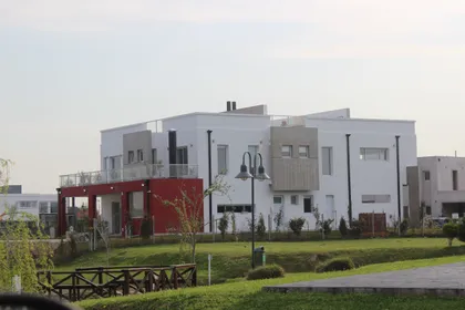 Fachada moderna blanca con detalles negros y ventanales amplios — proyecto Abierta al lago, por Marcela Romiti Arquitectura, en La Plata