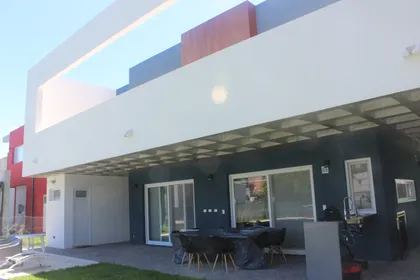 fachada moderna con patio y pergola de hormigón — proyecto Golondrinas 98, por Marcela Romiti Arquitectura, en La Plata