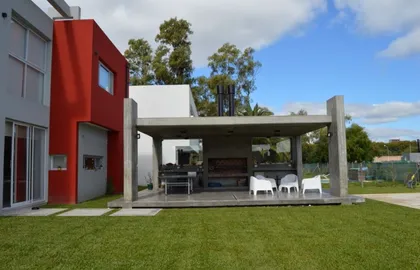 Amplio quincho moderno con pérgola de hormigón y mobiliario blanco — proyecto Golondrinas 99, por Marcela Romiti Arquitectura, en La Plata