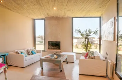 Living moderno con techo de hormigón visto y ventanales amplios — proyecto casa lc, por GARAGE arquitectura, en Mar del Plata