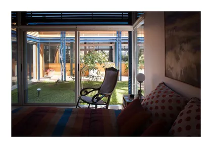 Living con gran ventanal al patio interior y sillón antiguo — proyecto Los Ceibos 60, por Mercedes klappenbach, en La Plata