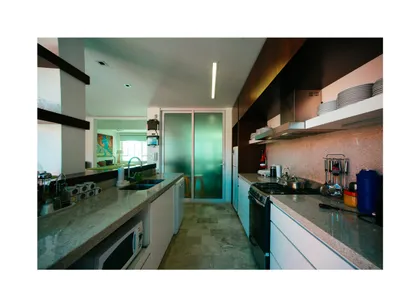 Cocina moderna con isla, mesadas de mármol y muebles de madera oscura — proyecto Calle 116, por Mercedes  klappenbach, en La Plata