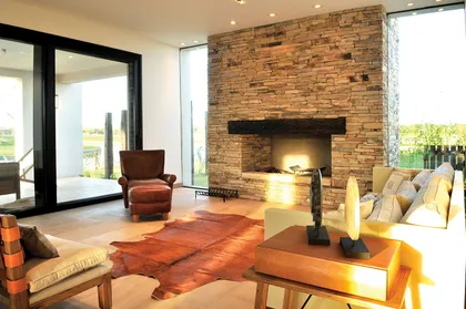 Sala de estar moderna con pared de piedra y chimenea — proyecto Casa Tigre, por Estudio Gamboa, en Tigre