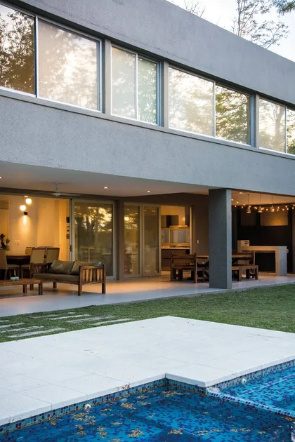 Casa moderna con pileta azul y terraza iluminada al atardecer — proyecto Casa 18, por Parrado Arquitectura