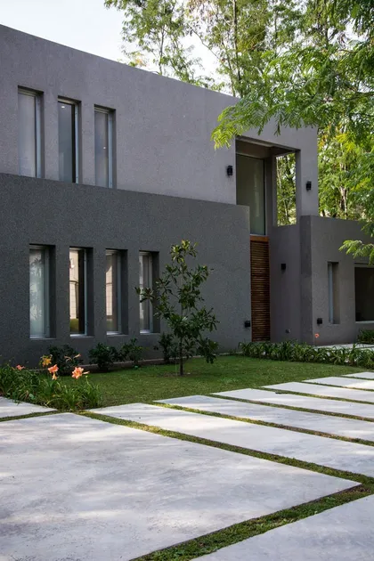 Casa moderna gris con sendero de hormigón y jardín natural — proyecto Casa 18, por Parrado Arquitectura