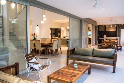 Terraza integrada con sala de estar, ventanales amplios y muebles de madera — proyecto Casa 18, por Parrado Arquitectura