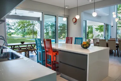 Cocina moderna con isla, ventanales amplios y vistas al jardín — proyecto Casa 18, por Parrado Arquitectura