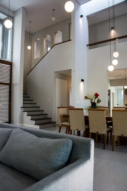 Escalera moderna doble altura iluminada con lámparas pendant en vivienda contemporánea — proyecto Casa 18, por Parrado Arquitectura