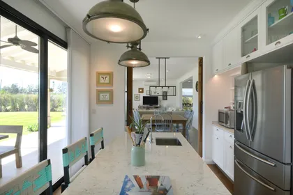 Cocina moderna con isla de mármol y vista al jardín exterior — proyecto Casa 16, por Parrado Arquitectura