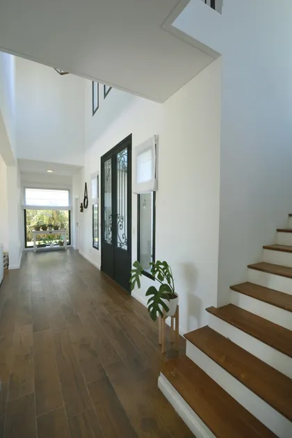Pasillo moderno con escalera de madera blanca y doble altura luminosa — proyecto Casa 16, por Parrado Arquitectura