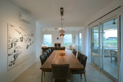 Comedor moderno con mesa de madera, sillas negras y ventanales amplios — proyecto Casa 17, por Parrado Arquitectura