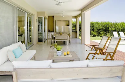 Terraza moderna con deck de madera, living blanco y vistas al jardín — proyecto Casa 13, por Parrado Arquitectura