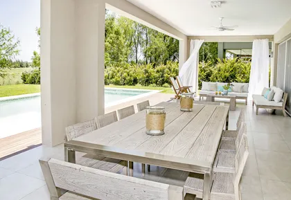 Galería abierta con mesa de madera, pileta y jardín al fondo — proyecto Casa 13, por Parrado Arquitectura