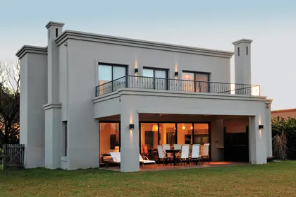 Casa moderna con fachada gris, amplios ventanales y galería iluminada — proyecto Casa 11, por Parrado Arquitectura