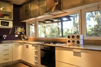 Cocina moderna con isla central, mesadas de mármol y amplios ventanales — proyecto Casa 9, por Parrado Arquitectura