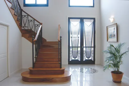 Escalera de madera curva con doble altura y puertas vidriadas al fondo — proyecto Casa 3, por Parrado Arquitectura