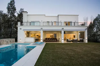 Casa moderna blanca con pileta, deck y amplios ventanales al atardecer — proyecto TRL 9, por Estudio Arq Daniel Tarrio
