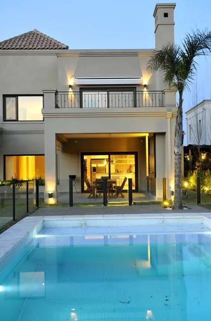 Casa moderna con pileta iluminada al atardecer y grandes ventanales — proyecto VO 19, por Estudio Arq Daniel Tarrio