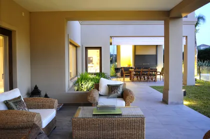 Terraza cubierta con muebles de rattan y vistas al living interior — proyecto VO 19, por Estudio Arq Daniel Tarrio
