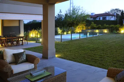 Terraza iluminada con pileta, muebles de rattan y amplio jardín — proyecto VO 19, por Estudio Arq Daniel Tarrio