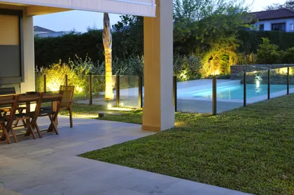 Patio moderno con pileta, jardín iluminado y porche techado al atardecer — proyecto VO 19, por Estudio Arq Daniel Tarrio