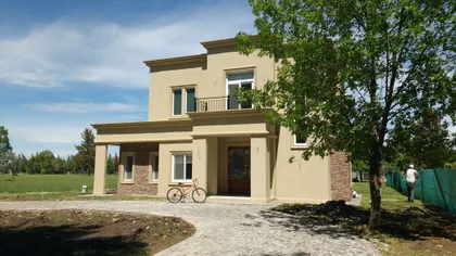 Casa moderna de dos plantas con fachada beige — proyecto Vivienda en Miralagos II, por Gabellini-Rey arquitectos, en La Plata