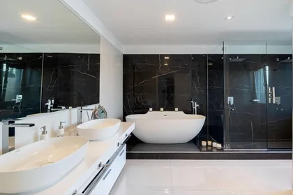 Baño moderno con bañera ovalada blanca y mármol negro — proyecto TRV 153, por Estudio Arq Daniel Tarrio